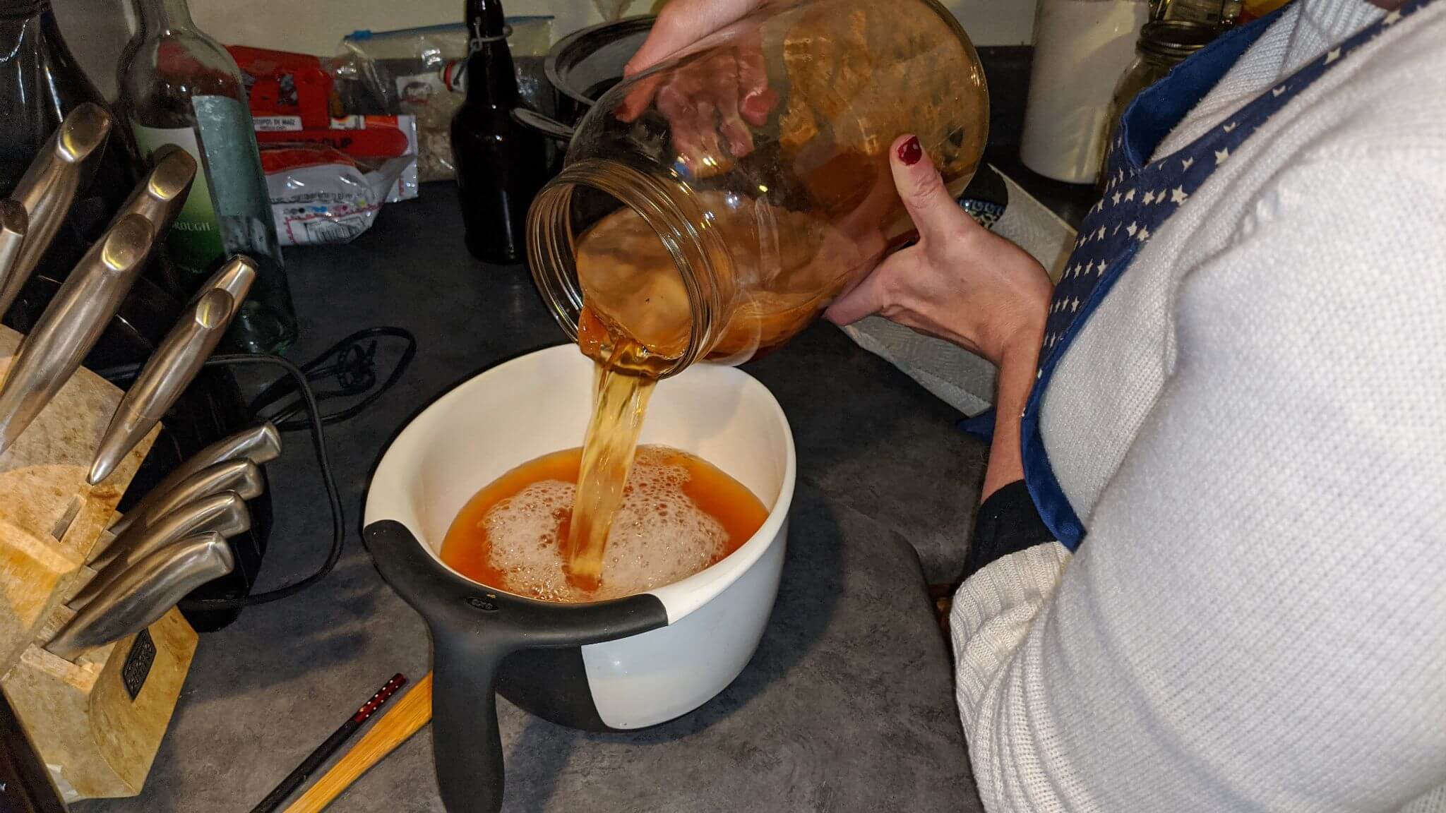Pouring kombucha into a handled pouring bowl