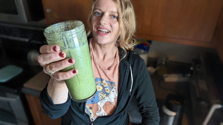 The Booch Witch holds a green smoothie