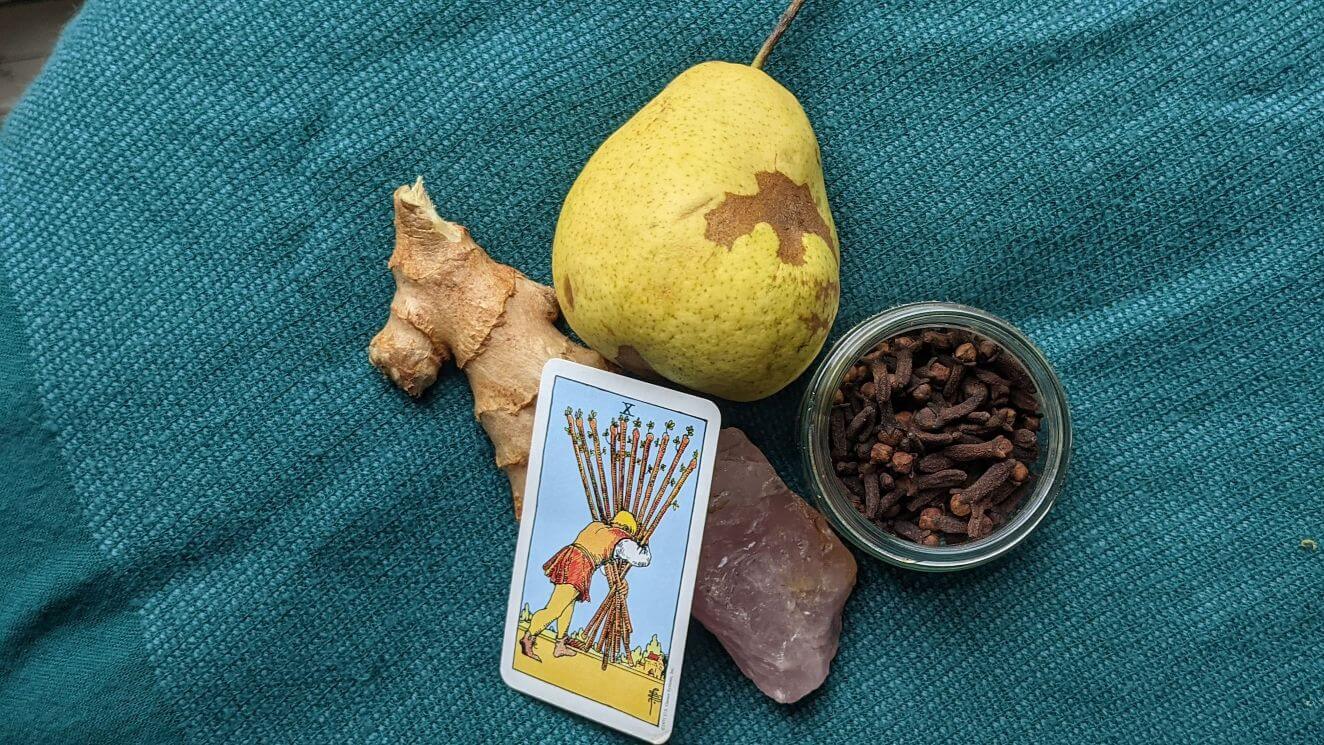 A fresh pair cits with fresh ginger and an upright ten of wands tarot card.