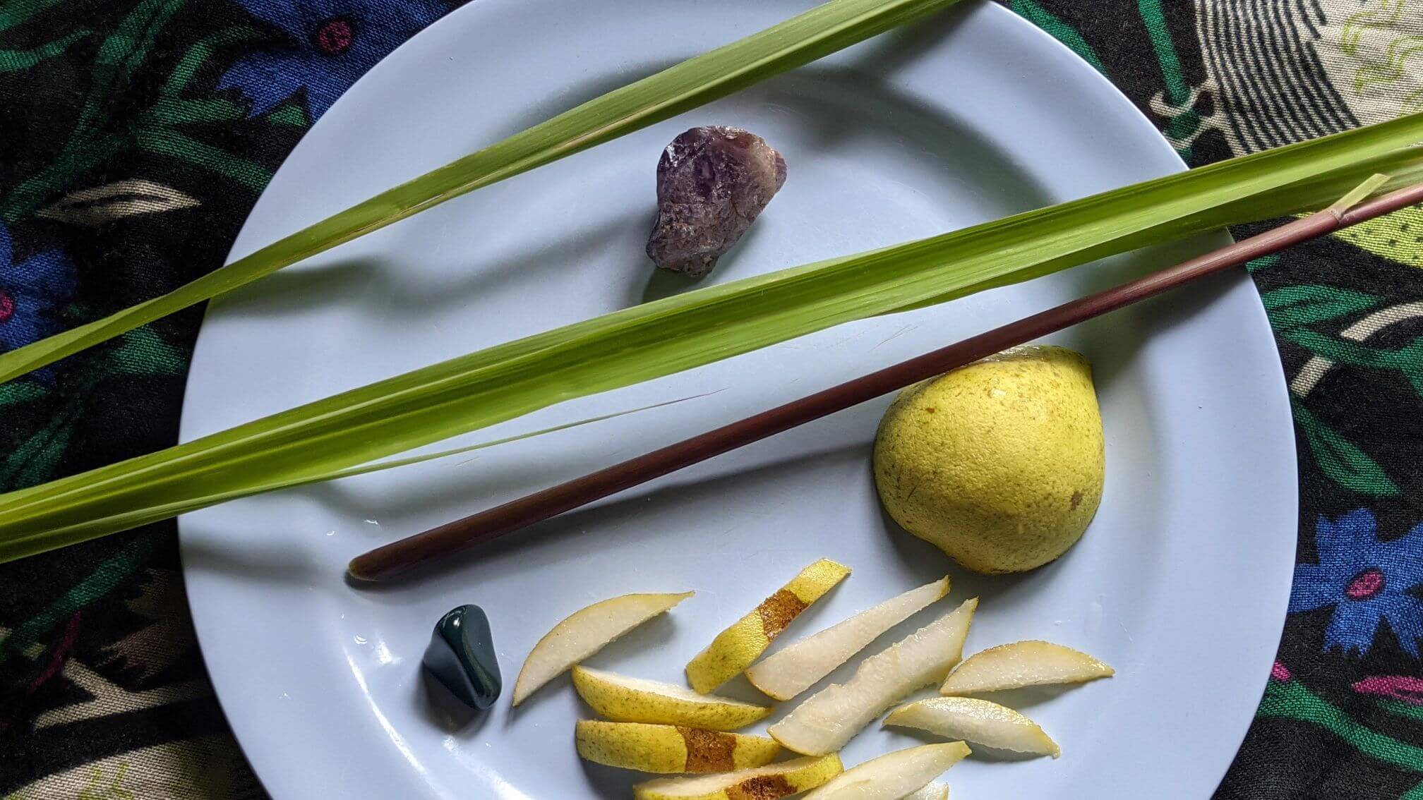 Fresh lemongrass sits on a plate with slices of fresh, juicy pear in natural light